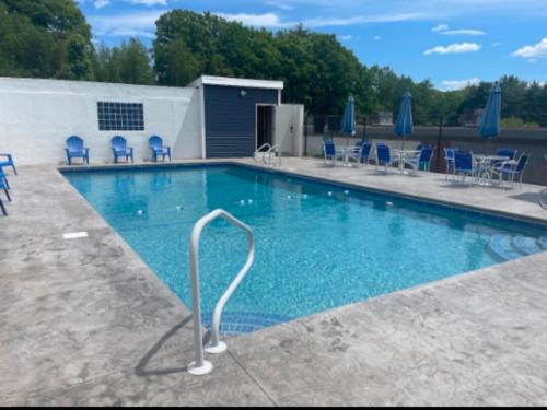 a large swimming pool with blue chairs and umbrellas at Lakeview Escape, Pool, Fast Wi-Fi & Free Parking in Laconia