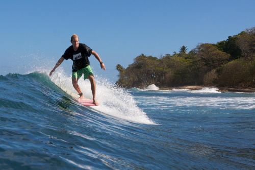 a man riding a wave on a surfboard in the ocean at Villa Sessions Entire House in Isabela