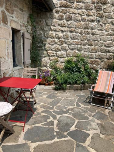 une table et des chaises rouges sur un patio en pierre dans l'établissement Gîte le Chiniacum, à La Celle-sous-Gouzon