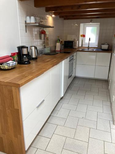 une cuisine avec des armoires blanches et un comptoir en bois dans l'établissement Gîte le Chiniacum, à La Celle-sous-Gouzon