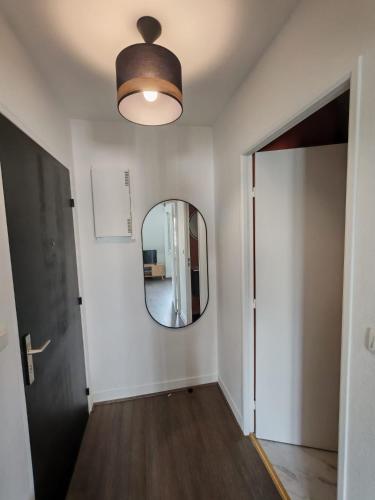 un couloir avec un miroir rond et une porte dans l'établissement Le Bel Horizon, à Chartres