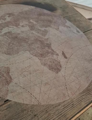 a map of the world on a wooden table at Tente glamping "Explorateurs" à la Ferme de la Chevêche in Fosses-La-Ville