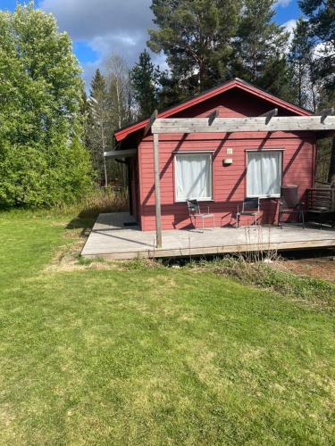 a red cabin with a deck and a yard at Mysig attefallare mitt i Vemdalen by in Vemdalen