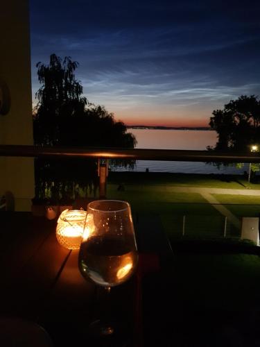 un bicchiere di vino seduto su un tavolo con una candela di Aloha Beach Terrace - Holiday Home a Siófok