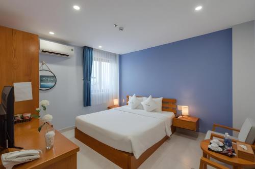 a bedroom with a bed and a desk with a phone at Stellar Hotel Phú Quốc in Phu Quoc