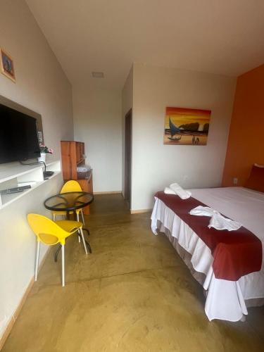 a bedroom with a bed and a table and a tv at Pousada Bugaendrus in Touros