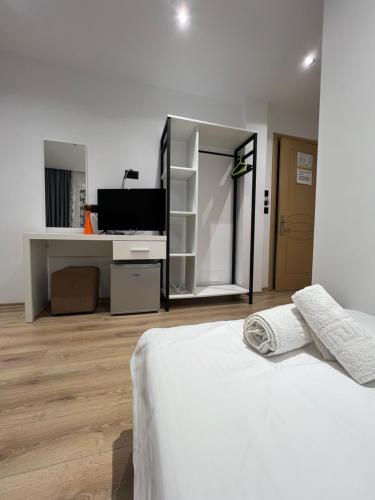 a white bedroom with a bed and a desk at Hotel Mario in Ksamil