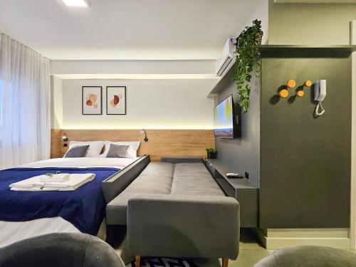 a bedroom with a bed with a couch next to it at Skyline Parque Moinhos by LikeHome in Floresta