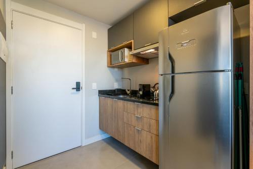 a stainless steel refrigerator in a kitchen with wooden cabinets at Skyline Parque Moinhos by LikeHome in Floresta