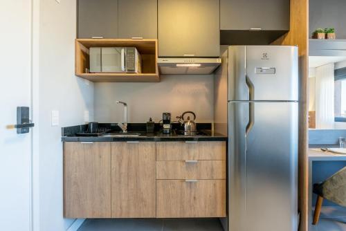 a kitchen with a stainless steel refrigerator and wooden cabinets at Skyline Parque Moinhos by LikeHome in Floresta