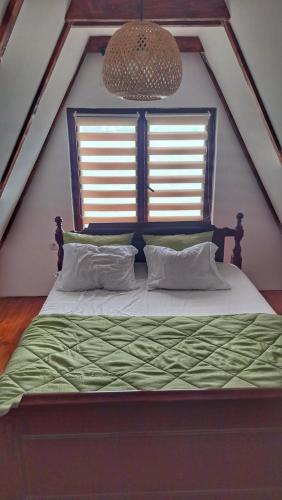 a bedroom with a bed with a green comforter and two windows at Kucica na Dunavu in Kovin