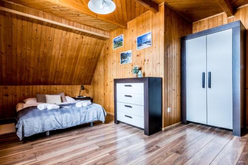 a bedroom with a bed and a wooden wall at Apartament Kalina-Mocarni in Kościelisko
