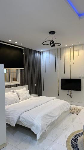 a bedroom with a large white bed and a flat screen tv at جنة الطائف in Taif