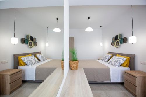 two beds in a room with two tables and pendant lights at RENI APARTMENT Faliraki in Faliraki
