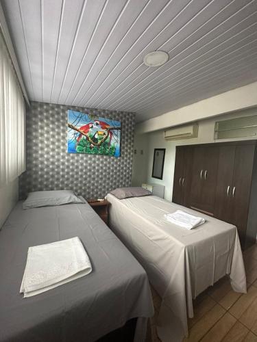 a room with two beds and a painting on the wall at Hotel Araras in Manaus