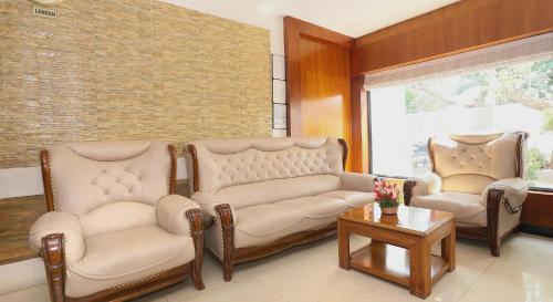 a living room with two couches and a table at Super Townhouse Dona Castle in Kollam