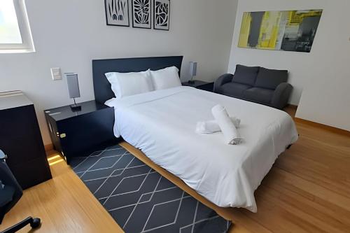 a bedroom with a large white bed and a chair at Residencial Ventana Polanco in Mexico City