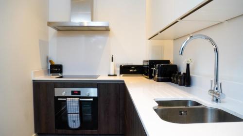 a kitchen with a sink and a stove at Manchester City Centre Apt with Balcony & Free Parking in Manchester