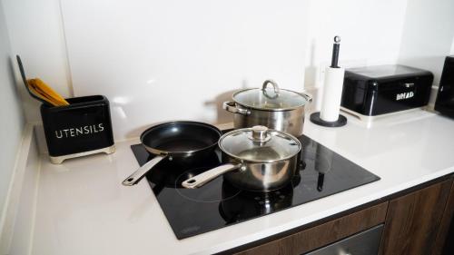 two pots and pans on a stove in a kitchen at Manchester City Centre Apt with Balcony & Free Parking in Manchester