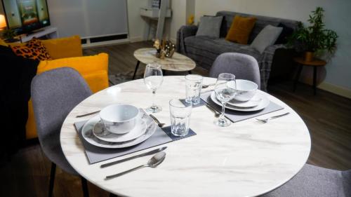 a white table with plates and wine glasses on it at Manchester City Centre Apt with Balcony & Free Parking in Manchester