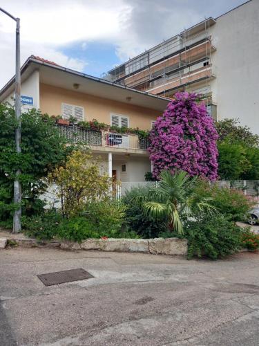 a building with pink flowers on the side of it at Rooms Mirjana in Trogir