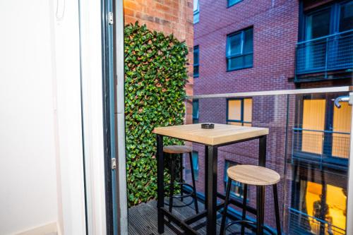 a balcony with a table and two stools at Manchester City Centre Apt with Balcony & Free Parking in Manchester