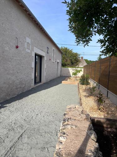 a driveway leading to a white building with a door at Gîte La Marnière in Luzillé
