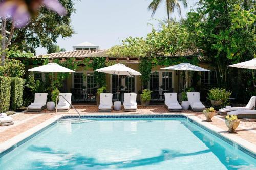 a swimming pool with lounge chairs and umbrellas at Hotel Escalante in Naples