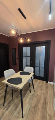 a dining room with a table and white chairs at Apartament Burgund 2 pokojowy z ogródkiem lub pokoje ze wspólną kuchnią i łazienką in Warsaw