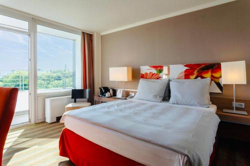 a hotel room with a large bed and a large window at SOALTEE Hotel by Trip Inn Frankfurt Messe Tagungshotel in Frankfurt/Main