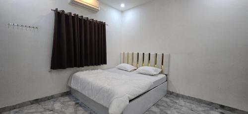 a small white room with a bed with a window at Shree Shiv bhakt niwas in Tuljapur