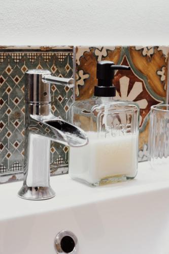 - un lavabo dans la salle de bains avec un distributeur de savon sur une étagère dans l'établissement Appartement de Charme hypercentre Bayonne, à Bayonne