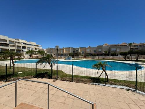 a swimming pool with palm trees and a fence at Sunset Beach Front in Almerimar