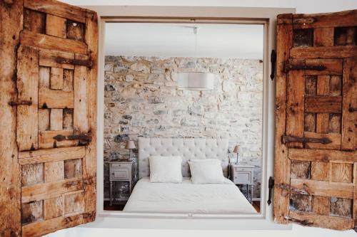 une chambre avec un lit blanc et un mur en pierre dans l'établissement Appartement de Charme hypercentre Bayonne, à Bayonne