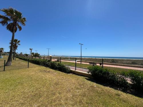 a park with a palm tree next to the beach at Sunset Beach Front in Almerimar