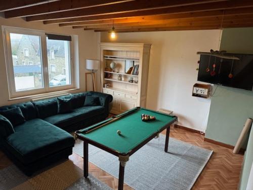 a living room with a couch and a pool table at la maison des souvenirs précieux in Surtainville