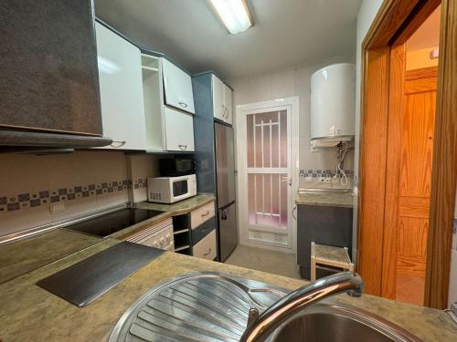 a kitchen with white cabinets and a sink at Sunset Beach Front in Almerimar