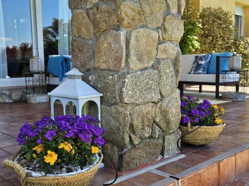 two baskets of flowers and a bird house on a patio at Villa Prana in Avila