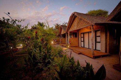 a small house with a deck next to a building at African Excursions Guest lodge in Khwai