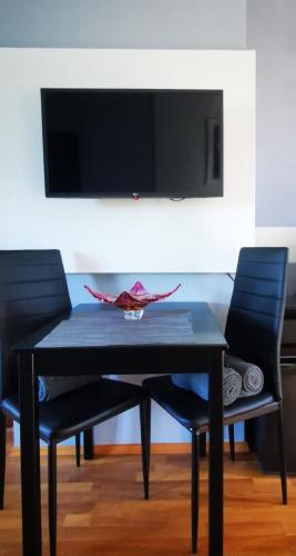 a black table with two chairs and a tv on a wall at M3 Green Oasis Mogyoród in Mogyoród