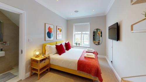 a bedroom with a large bed with red pillows at Madison Hill - White Hill House 4 - 2 bedroom flat in London