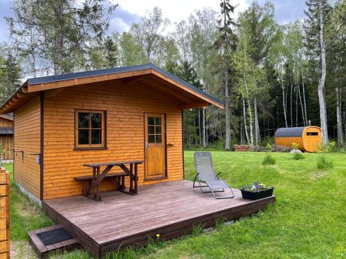 eine Hütte mit einer Holzterrasse, einem Tisch und einem Stuhl in der Unterkunft Marika Puhkeküla - Metsanurga Öömaja "shared bathroom" in Nõva