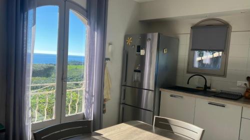 a kitchen with a refrigerator and a table and a window at villa vue mer avec piscine et jardin arboré in Coggia
