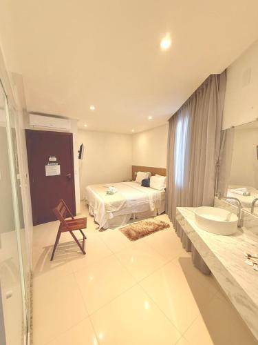 a bathroom with a bed and a sink and a tub at Vila do Morro Pousada in Morro de São Paulo