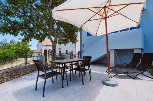 a table and chairs with an umbrella on a patio at Domus Olivae in Nerezine