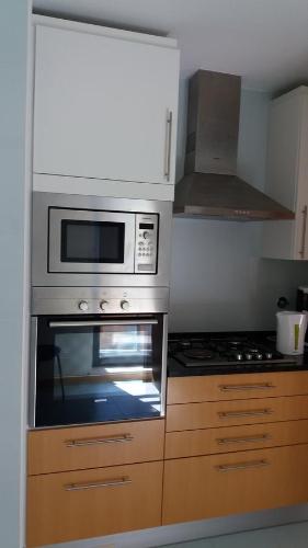a kitchen with a stove and a microwave at Apartamento Novo com Piscina Olhão in Olhão
