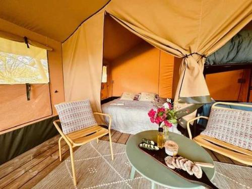 une chambre avec une tente avec un lit et une table dans l'établissement Camping 4 étoiles - Piscine - eeciaf, à Meyronne