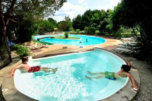 two boys swimming in a pool at a water park at ZEcamping 4 étoiles pataugeoire piscine chiens acceptés tente 25m2 in Meyronne