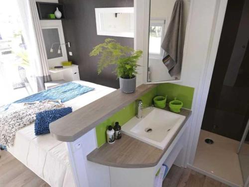 un piccolo bagno con lavandino e letto di Camping 4 étoiles - Piscine - eeebgi a La Faute-sur-Mer