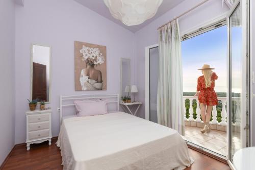 a bedroom with a bed and a woman standing on a balcony at Villa Mitsekou in Prinos